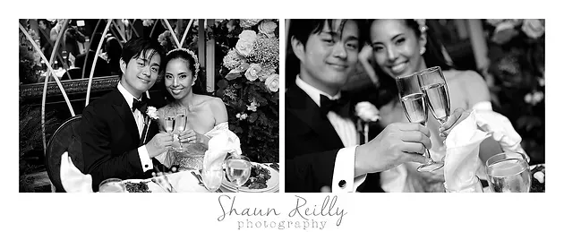 Black-and-white wedding couple posing and smiling, holding a bouquet and champagne glasses