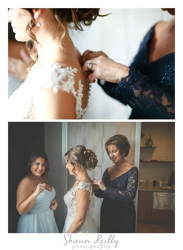 Bride getting her dress fastened, with a bridesmaid in a navy lace dress assisting indoors