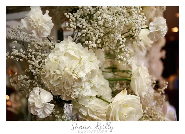 White roses and baby’s breath arranged in a soft, elegant floral bouquet.