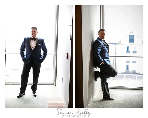 Formal portrait of a man in a blue suit posing by a window in a bright modern interior