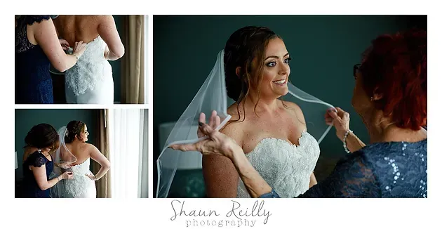Bride being helped into a white wedding dress while smiling with a bridesmaid in a blue dress