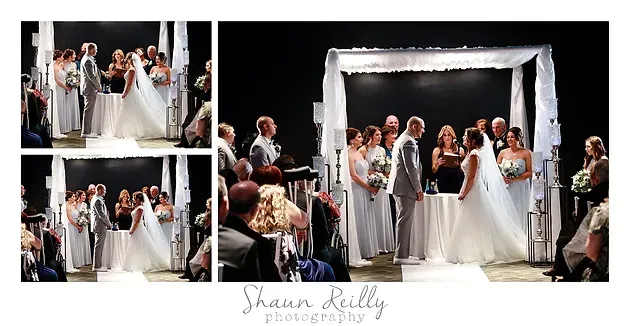 Wedding party on a lit stage beneath a white canopy, with a bride and guests posed in formal attire.