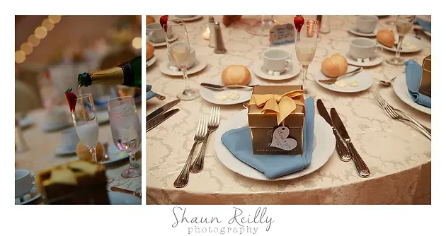 Elegant banquet table with white dishes, bread rolls, wine glasses, and a cake centerpiece on a blue plate