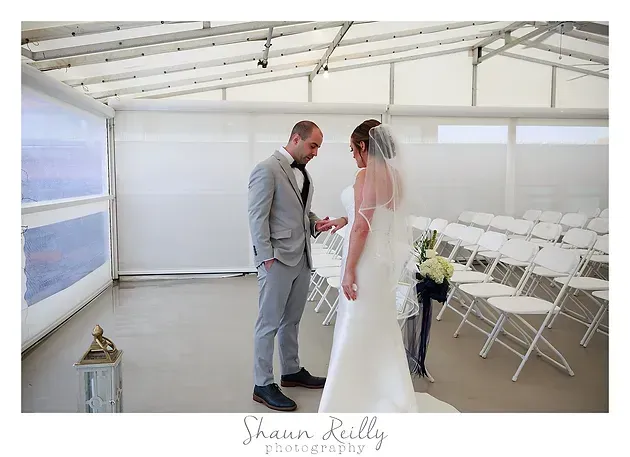 Bride and groom standing in a bright white wedding chapel, facing each other during the ceremony