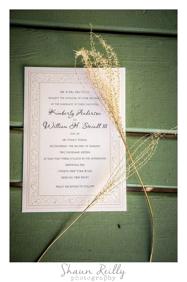 Elegant white wedding invitation with dried grass on a green background