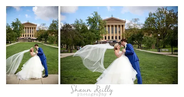 Bride and groom kissing in a garden, her veil flowing, with a classical building in the background.