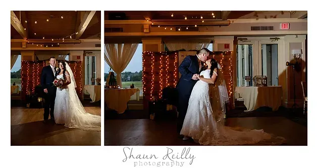 Bride and groom dancing in a warmly lit wedding reception hall, with draped windows and string lights.