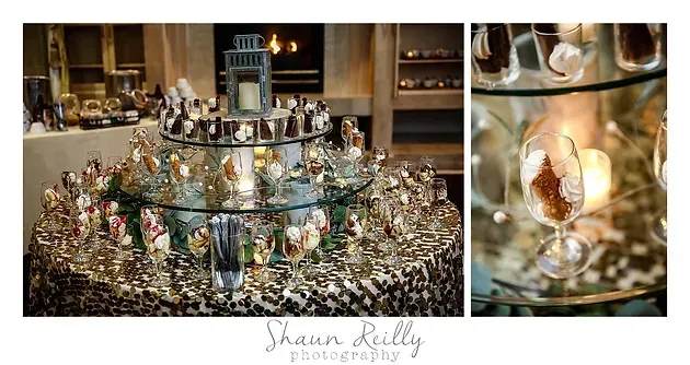 Elegant dessert display with gold-wrapped treats and glass jars on a tiered stand in a warm buffet setting
