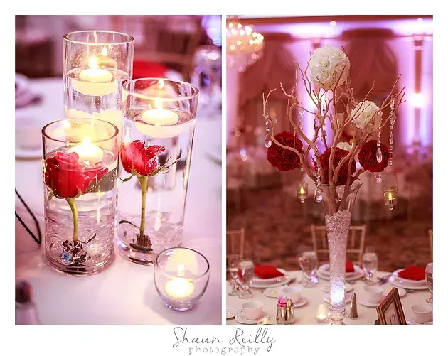 Pink candlelit table centerpieces with red flowers in tall glass vases and votive candles