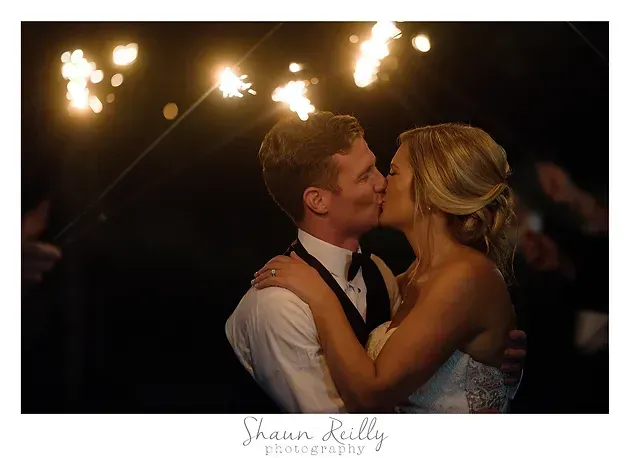 Couple kissing in formalwear under glowing sparklers at night