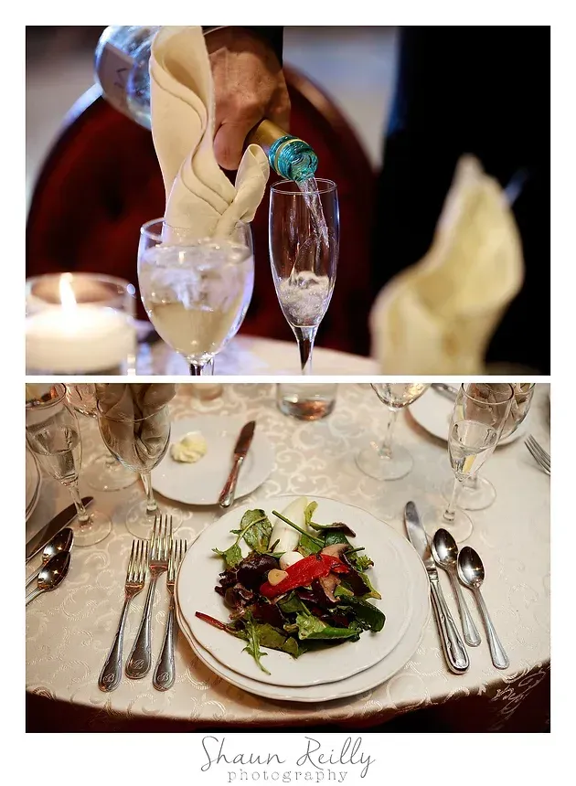 Server pouring wine into glasses at a candlelit restaurant table with salad and silverware