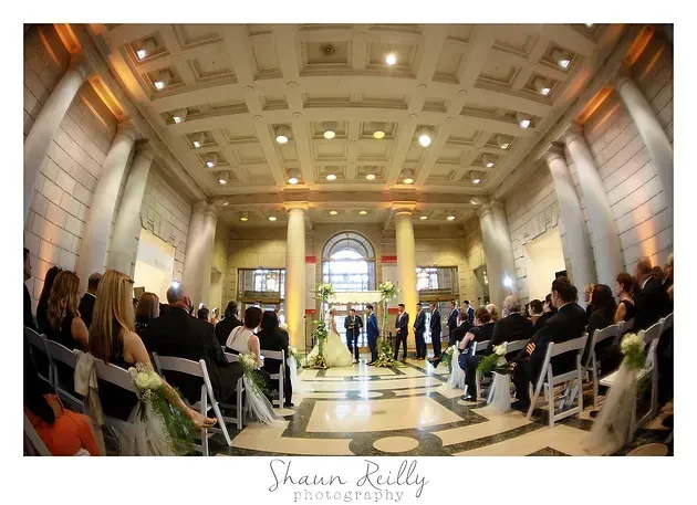 Guests seated in a grand hall watch a ceremony at the altar-like front entrance