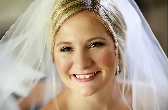 Smiling bride in a white veil and dress, looking at the camera