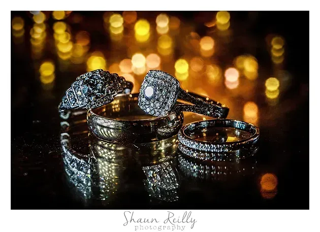 Diamond rings on a reflective surface with warm gold bokeh lights in the background