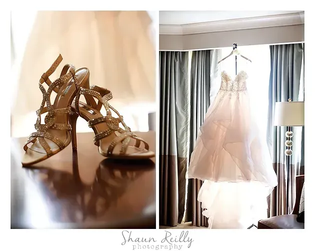 Gold wedding shoes beside a white bridal gown hanging by a window