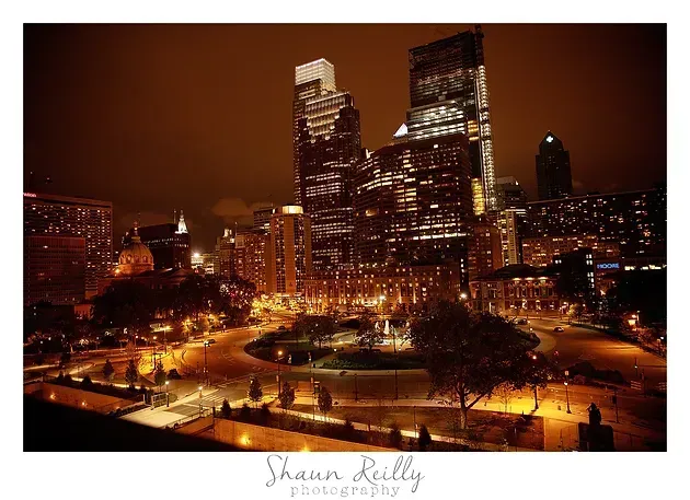 Night city skyline with glowing skyscrapers and streetlights in warm orange tones