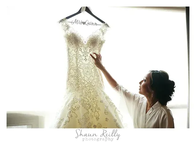 Bride admiring a lace wedding dress hanging in a bright window