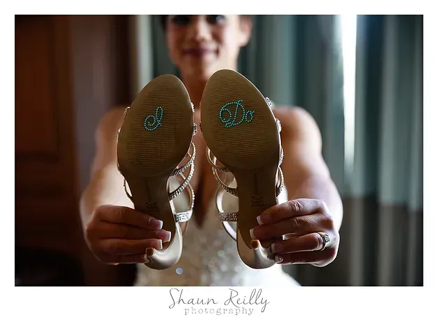 Person holding up the soles of athletic shoes toward the camera in a bright indoor room