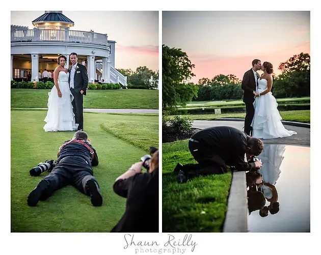 Wedding couple posing by a mansion while photographer lies on the lawn capturing their reflection in a puddle