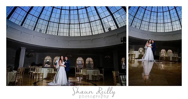 Bride in white gown poses in a bright domed ballroom with arched windows and tables
