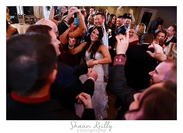 Guests dancing and raising hands at a lively indoor party with warm lighting