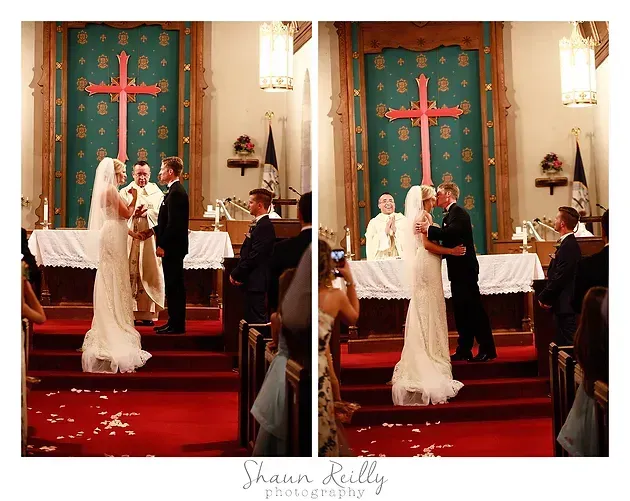 Bride and groom stand at the altar in a church with a red-carpeted aisle and green backdrop.