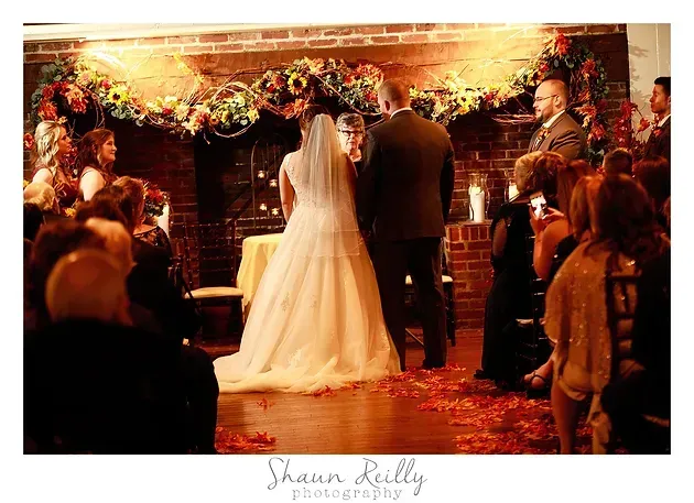 Bride and groom exchange vows at a candlelit wedding ceremony with guests watching