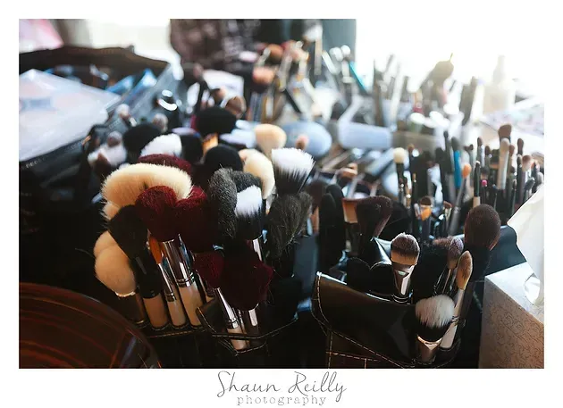 Assorted makeup brushes in containers, with soft white and black bristles in a bright vanity setting
