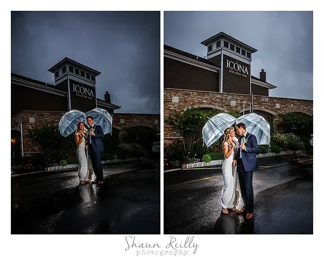 Couple under clear umbrella in rainy parking lot beside stone building at dusk