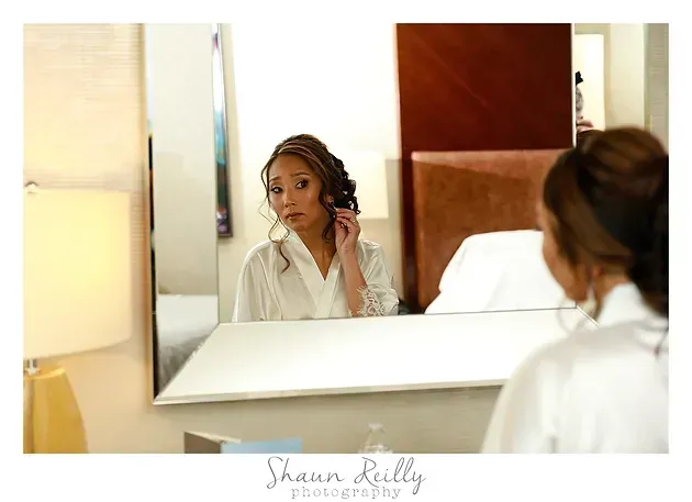 Woman in white robe looking into a mirror in a softly lit bedroom