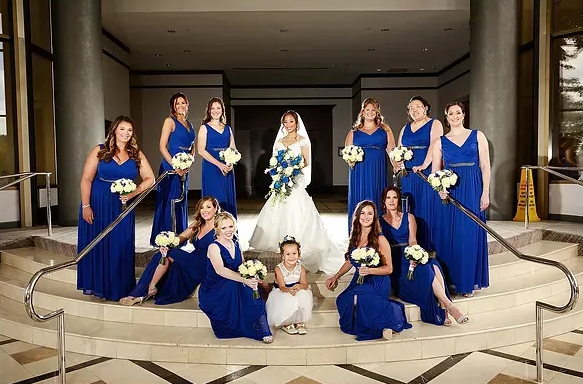 Wedding party in blue dresses posing on a staircase with bride and flower girls