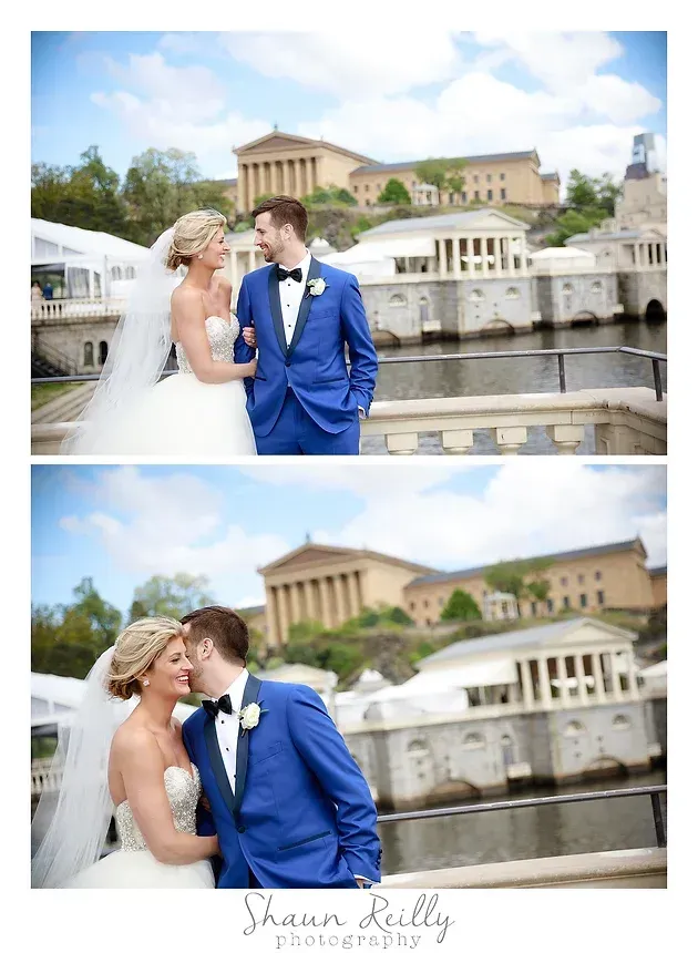 Bride and groom in white and blue wedding attire by a waterfront, kissing with a villa in the background