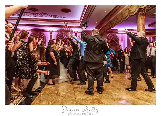Guests dancing at a formal reception with purple lighting and gold-trimmed ballroom decor