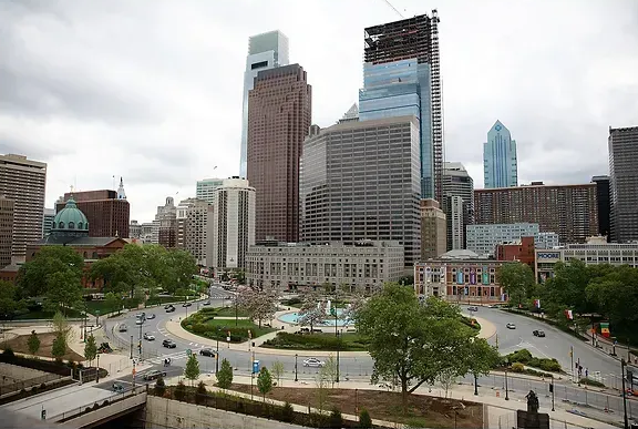 Downtown skyline with tall buildings and a park plaza under cloudy skies