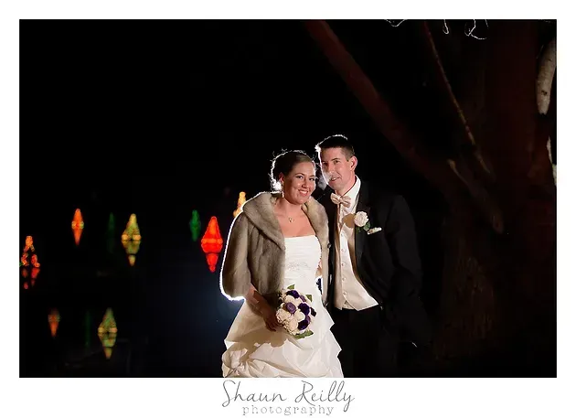 Bride and groom pose at night with colorful lights in the background