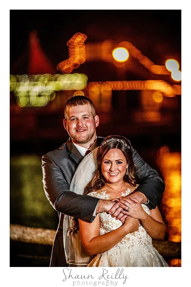 Couple embracing outdoors at night with warm bokeh lights in the background