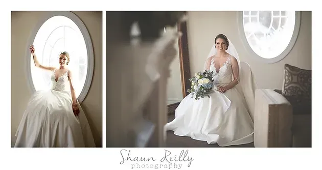 Bride in white gown posing in a bright room, seated by a round window with a bouquet beside her