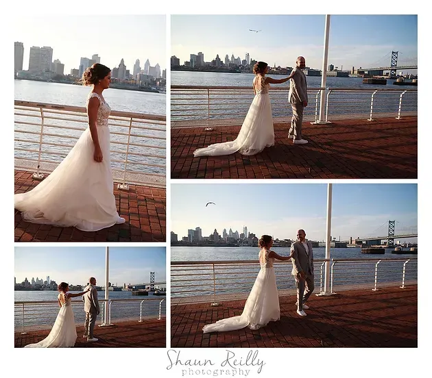 Bride and groom in wedding attire by a waterfront railing with city skyline in the background