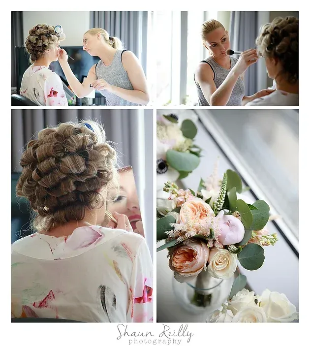 Bride getting hair and makeup done beside a floral bouquet in a bright room