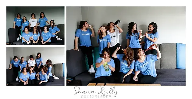Group portrait of people in matching blue shirts posing indoors against a white wall.