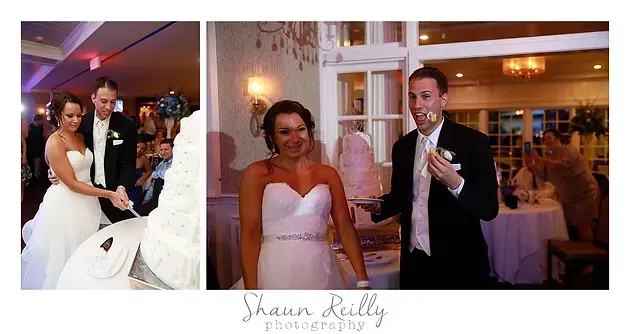 Wedding couple smiling at reception, with bride in white gown and groom in black tuxedo beside a cake table