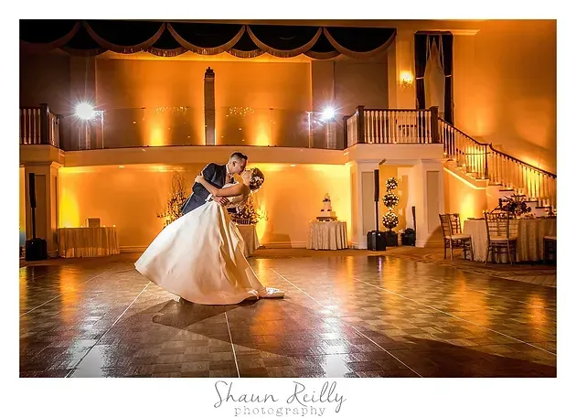 Bride and groom dancing in an elegant, warmly lit ballroom at their wedding