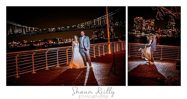 Couple in wedding attire on a lit bridge at night, with city lights and water in the background.