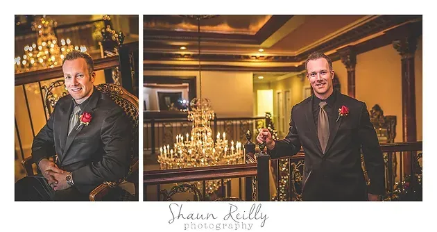 Formal portrait of a man in a dark suit and red boutonniere, posed in a warmly lit, elegant venue.