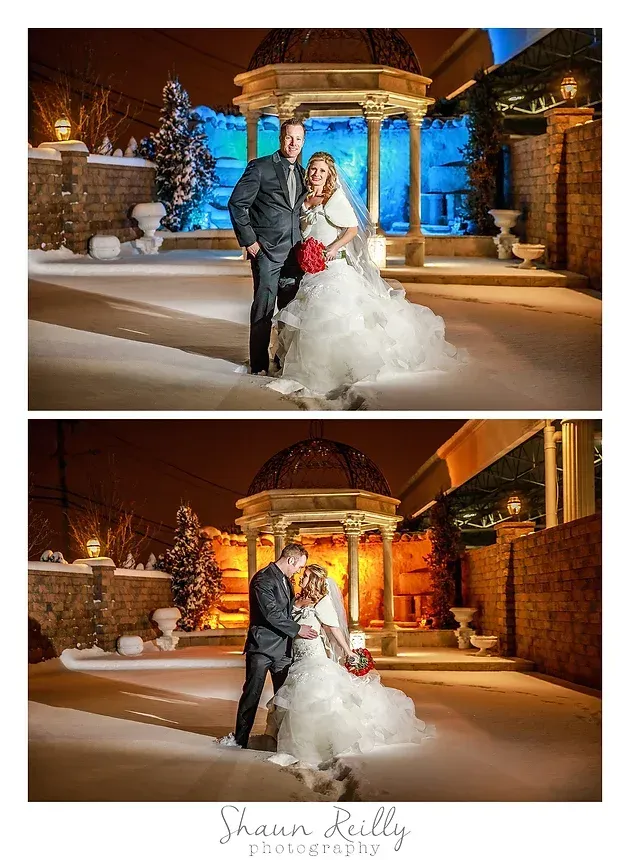 Bride and groom pose in a snowy, warmly lit outdoor venue at night.