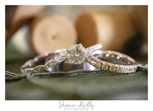 Diamond rings stacked on a green surface, with soft-focus wooden candles in the background