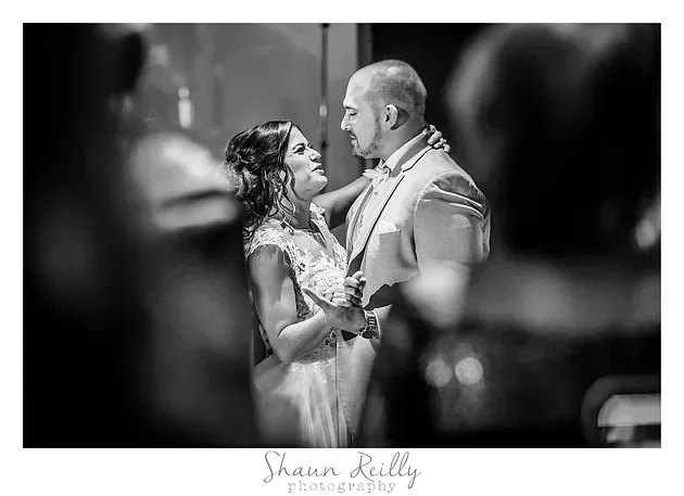 Black-and-white wedding portrait of a couple sharing a tender gaze while standing together indoors