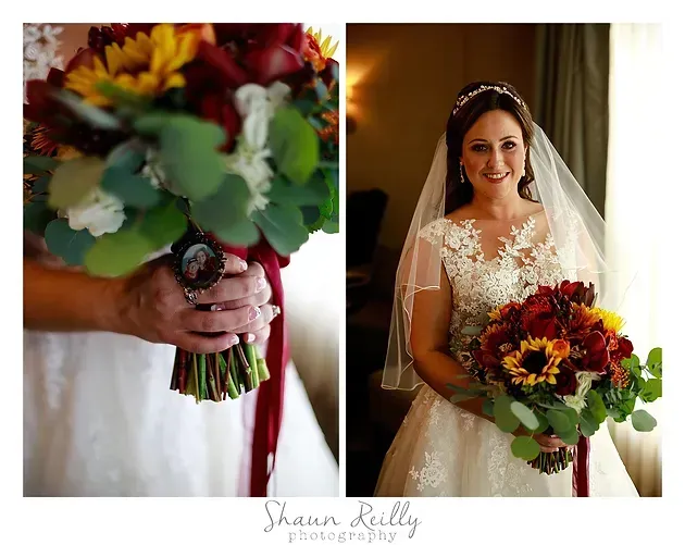 Bride holding a red-orange bouquet, smiling in a white dress and veil by a window