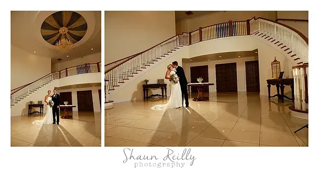 Couple dancing in a grand lobby beneath a curved staircase, warm beige interior.
