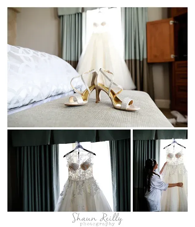 Gold bridal shoes, white wedding dress on hanger, and bride admiring it in a softly lit bedroom